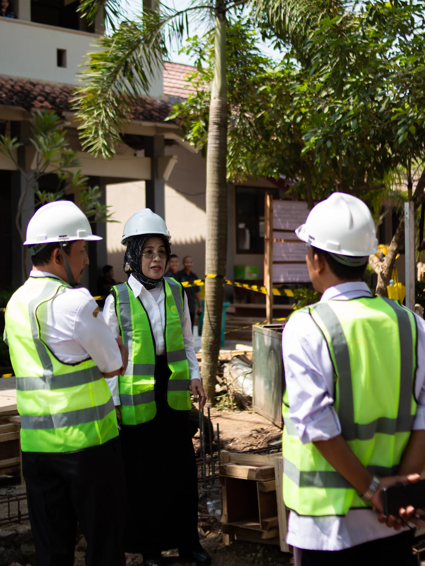 Site team in hard hats and safety vests discussing plans outdoors